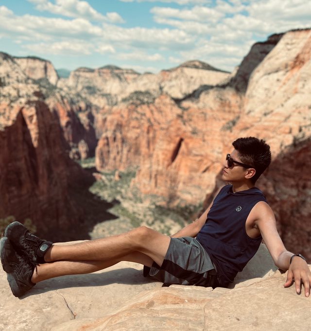 Leo resting at a canyon overlook, surrounded by sweeping rock formations.