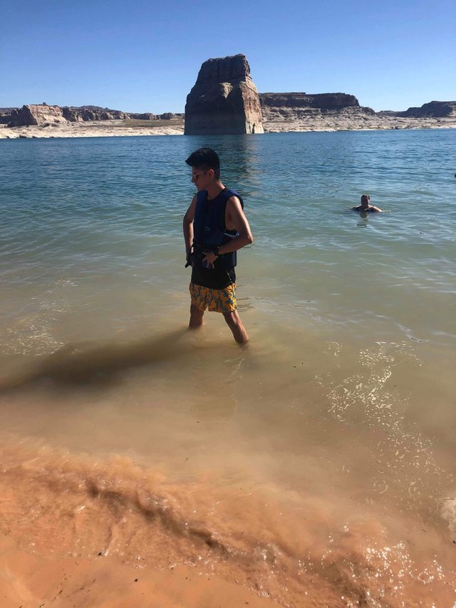 Leo wading in a lake with a sandstone formation in the distance.