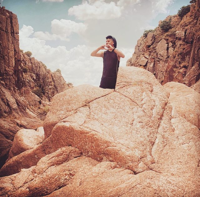 Leo making a heart shape with his hands among warm-colored canyon rocks.