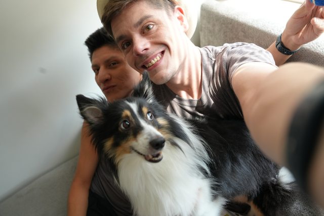 Leo and Chris smiling together with Scout at home.